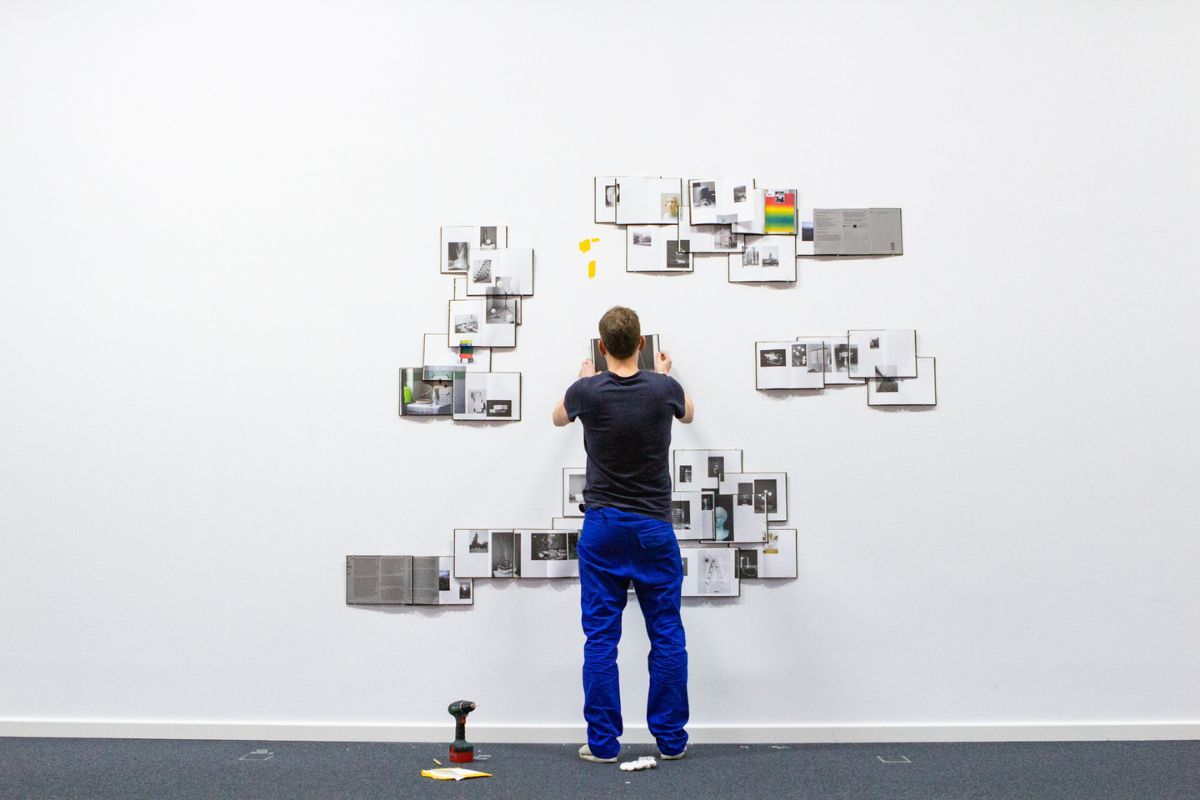 Der Künstler Peter Puklus installiert 35 Exemplare seines Buches "Handbook to the Stars" an einer Wand im Wilhelm-Hack-Museum in Ludwigshafen für die Ausstellung der Biennale für aktuelle Fotografie 2020.